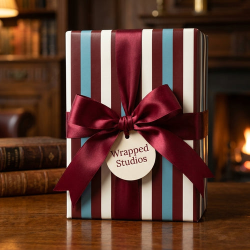 Luxury striped wrapping paper in burgundy, cream, and blue with a satin bow, by Wrapped Studios.
