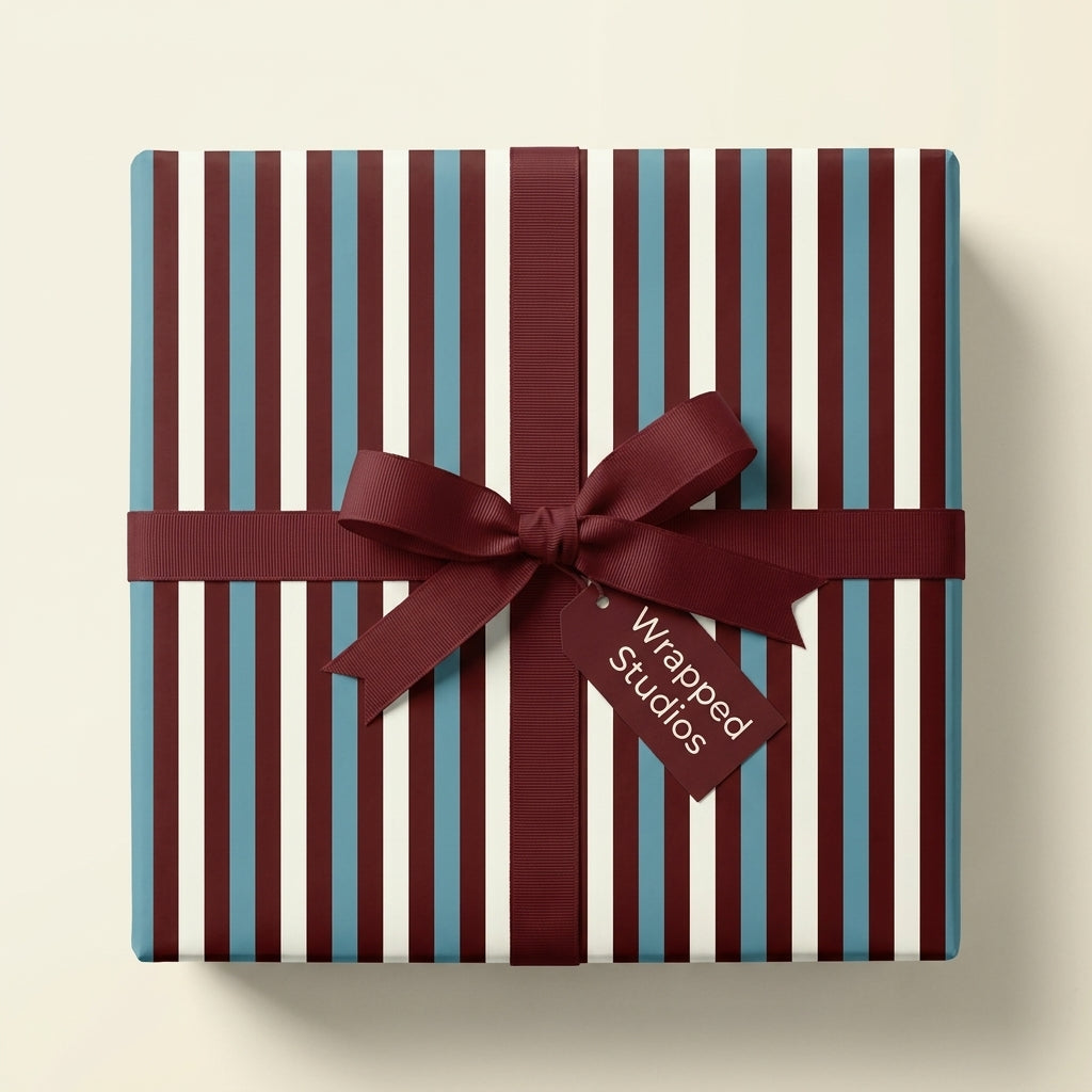 Burgundy and blue striped wrapping paper on a square gift box with a luxury bow by Wrapped Studios.