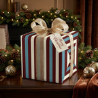 Luxury striped Christmas wrapping paper in burgundy, cream, and blue with a gold bow by Wrapped Studios.