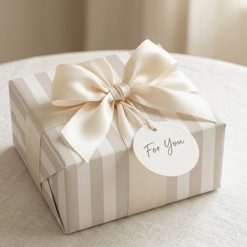 Elegant beige striped gift wrap with a cream satin bow and "For You" tag, from Wrapped Studios.