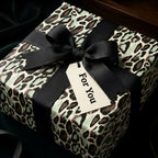 Luxury leopard print wrapping paper in mint green with a black ribbon and gift tag by Wrapped Studios.