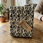 Mint green leopard print wrapping paper by Wrapped Studios, tied with rustic twine and an 'Enjoy' tag.