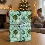 Green Christmas wrapping paper with vintage ornament patterns and silver twine by Wrapped Studios.