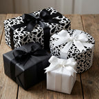 Elegant black and white paisley wrapping paper and solid monochrome gift boxes with satin ribbons, arranged on a rustic wooden table.