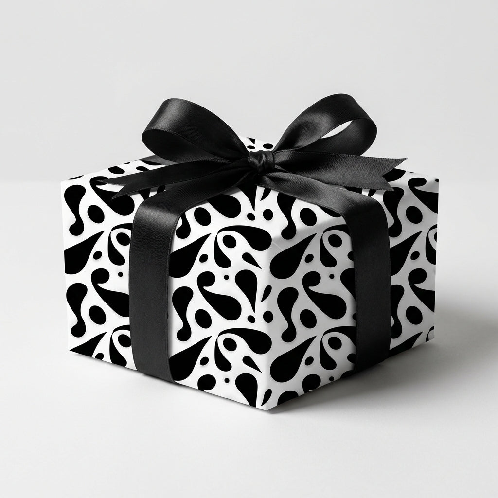 Elegant black and white abstract patterned wrapping paper on a square gift box, tied with a black satin ribbon bow for a modern look.