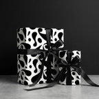 Luxury black and white abstract wrapping paper on two gifts tied with elegant black satin bows.