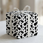 Chic black and white abstract wrapping paper on a gift box tied with a white ribbon bow.