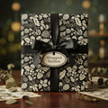 Elegant gift wrapped in black floral wrapping paper with a satin ribbon and bow.
