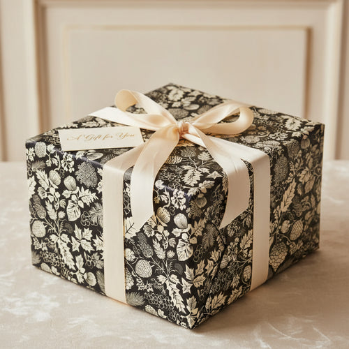 Elegant gift wrapped in botanical black floral wrapping paper with a cream ribbon and "A Gift for You" tag.