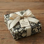 Elegant floral wrapping paper in black and cream, tied with a wide ribbon and gift tag.