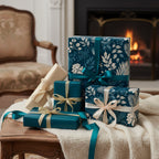 Elegant gifts wrapped in teal floral wrapping paper with satin ribbons, displayed in a cozy, fireside setting.