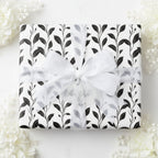 Elegant gift wrapped in black and white floral wrapping paper, tied with a sheer white ribbon.