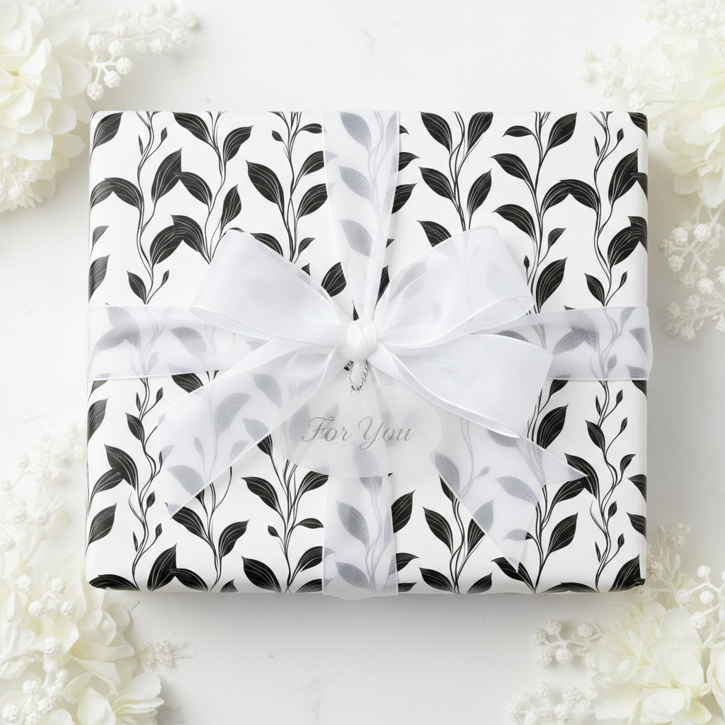 Elegant gift wrapped in black and white floral wrapping paper, tied with a sheer white ribbon.