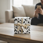 Wrapped Studios floral wrapping paper featuring a black leaf pattern and cream ribbon.