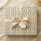 Elegant gift wrapped in floral wrapping paper with a gold satin bow and "Joy to You" gift tag.