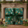 Elegant Christmas gift wrapped in green floral wrapping paper with a velvet ribbon and "Holiday Cheer" tag.