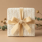 Elegant gift wrapped in cream floral wrapping paper with a gold velvet ribbon and bow.