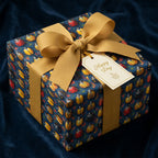 Navy birthday wrapping paper with ladybug print. Gift is tied with a gold ribbon and "Happy Day" tag.