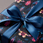 Close-up of a gift wrapped in insect wrapping paper with a satin blue bow.