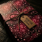 Burgundy Christmas gift wrap with snowflake and star pattern, tied with rustic twine and gift tag.