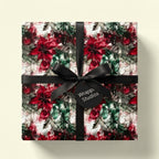 Wrapped gift in floral Christmas wrapping paper with a black bow. Wrapped Studios.