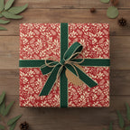 Elegant Christmas gift wrap: Red floral paper with green ribbon and a blank tag on a rustic wood background.