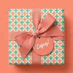 Modern geometric gift wrap with teal and coral plus pattern and pink ribbon bow by Wrapped Studios.