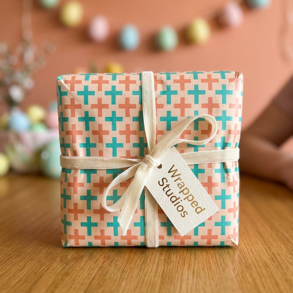 Modern wrapping paper with teal and coral plus signs, cream velvet ribbon, and gift tag by Wrapped Studios.