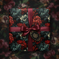 Elegant floral wrapping paper featuring red and teal blooms, tied with a satin burgundy ribbon and gift tag.