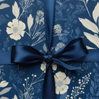 Elegant navy blue floral wrapping paper with a satin bow tied on a wrapped gift box.