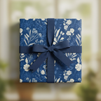 Navy blue square gift box with elegant white floral wrapping paper and matching ribbon bow.