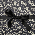 Elegant floral wrapping paper in navy and cream, adorned with a classic black satin bow.