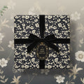 Elegant navy floral wrapping paper with a velvet ribbon and gift tag, perfect for special occasions.