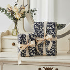 Navy floral wrapping paper with blush ribbon on gifts, displayed in elegant home setting.