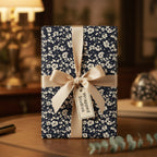 Elegant gift wrapped in navy floral wrapping paper with a gold ribbon.