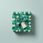 Wrapped gift with a green floral wrapping paper, tied with matching ribbon and branded tag.