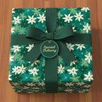 Teal floral wrapping paper with dark green ribbon, bow, and "Special Delivery" tag, ideal for holiday gifts.