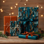 Stylish Christmas gifts wrapped in tree-patterned paper with teal and brown ribbon, on a wood table.