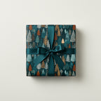 Teal Christmas gift wrap with a tree pattern tied with a satin ribbon bow.