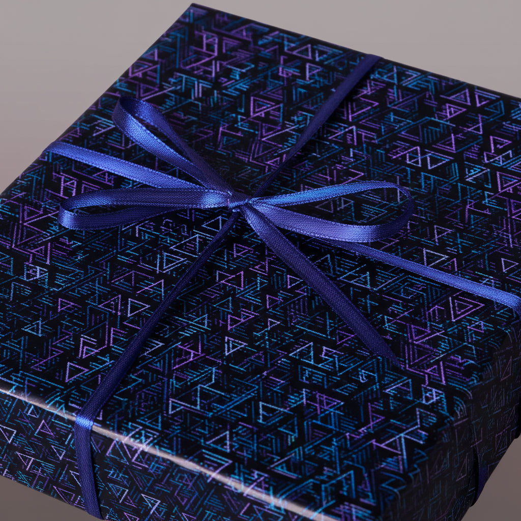 Geometric wrapping paper in teal and purple with a satin blue ribbon, perfect for birthday gifts.