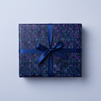 Dark modern wrapping paper with blue and purple geometric design, tied with a blue satin bow.