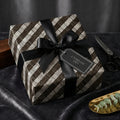 Elegant woven pattern wrapping paper with a black satin ribbon and gift tag for a timeless present.