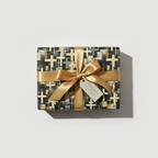Modern wrapping paper with a gold satin ribbon, featuring a geometric cross pattern in gray, black, and gold.