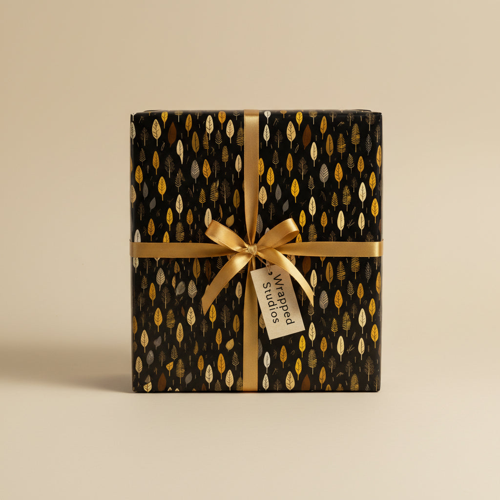 Elegant black gift wrapped in leaf-patterned paper with a gold ribbon bow.