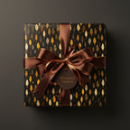 Elegant gift wrapped in black wrapping paper with gold leaf pattern and brown satin ribbon bow.