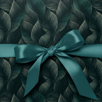 Elegant gift wrapped in dark teal leaf-patterned paper with matching satin ribbon.
