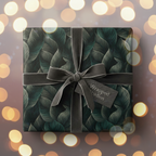 Elegant gift box wrapped in dark green botanical wrapping paper with velvet ribbon.