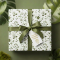 Elegant floral wrapping paper with green ribbon and a gift tag.