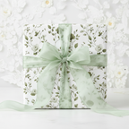 Elegant gift wrapped in white floral wrapping paper with sage green ribbon.