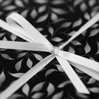 Elegant gift wrapped in black and white floral wrapping paper, tied with a white satin ribbon.
